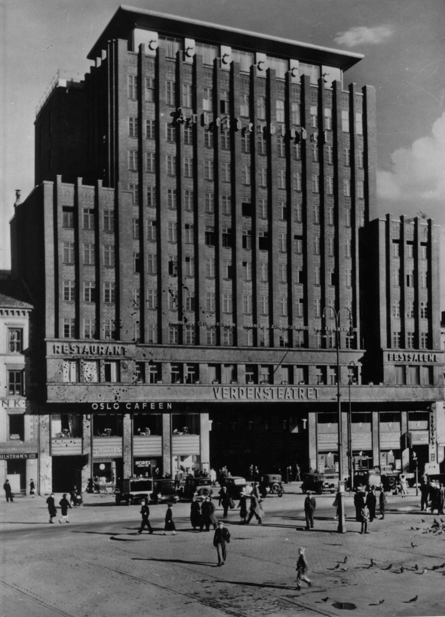 Folketeaterbygningen på Youngstorget i Oslo sett fra torget, med mennesker og biler foran. Her hadde bl.a. Arbeiderbladet sine lokaler frem til 2. verdenskrig. Under krigen tok Quisling-avisen "Fritt Folk" over lokalene.