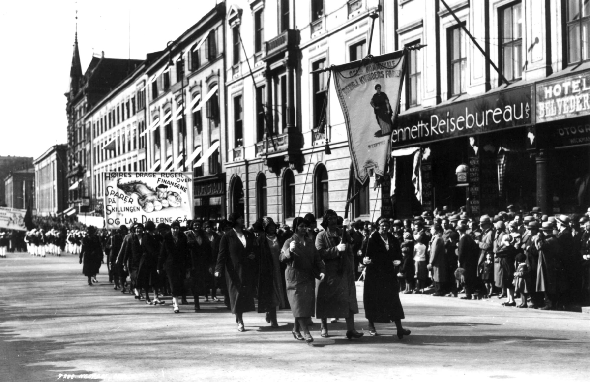 1. mai-demonstrasjon, Karl Johans gate, Oslo, 1930. Oslo kommunale rengjøringskvinner i tog med faner. Tilskuere på fortauet.
