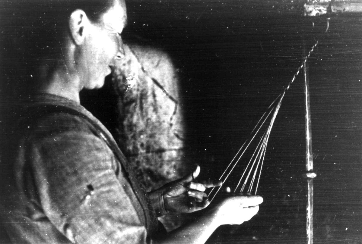 Bråtådal, Skjåk, Oppland 1941. Ragnhild Horte bregder enkle sokkebånd av ulltråd.