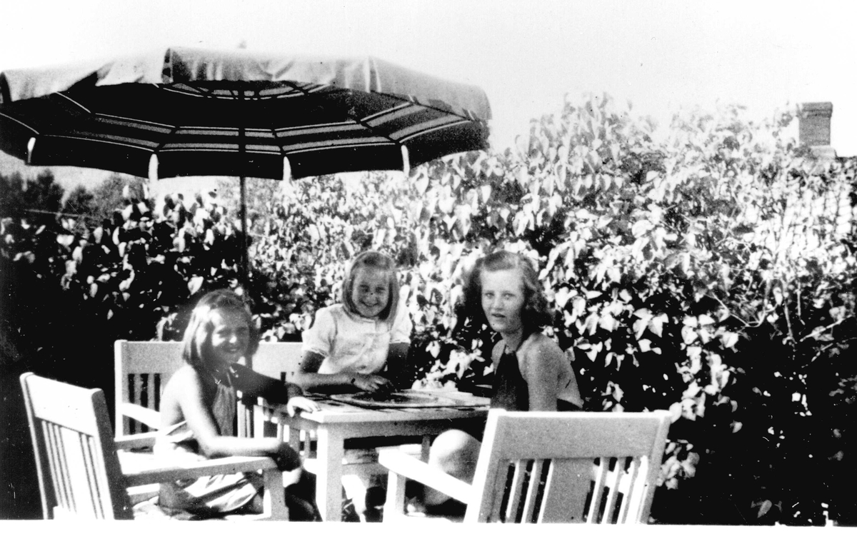 Familiens datter Jorunn Fossberg og venner i sommerhusets hage på Nærsnes i Røyken, Buskerud, tatt ca.1937, mens de spiller "Monopol". 
Fra Jorunn Fossbergs familiealbum.