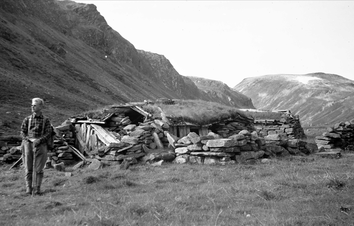 Rester av setertun, Romfosetra, Ottdalen, Sunndal, Møre og Romsdal. Mann med vandrestav i forgrunnen. Fotografert 1940.