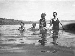 Voksne og barn kledd med badedrakt bader i sjøen. Robsahm og