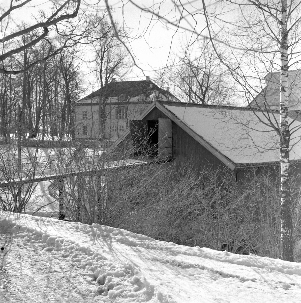 Eidsvollsbygningen, Eidsvoll, 08.04.1958. Sett bak uthus. Vinter.