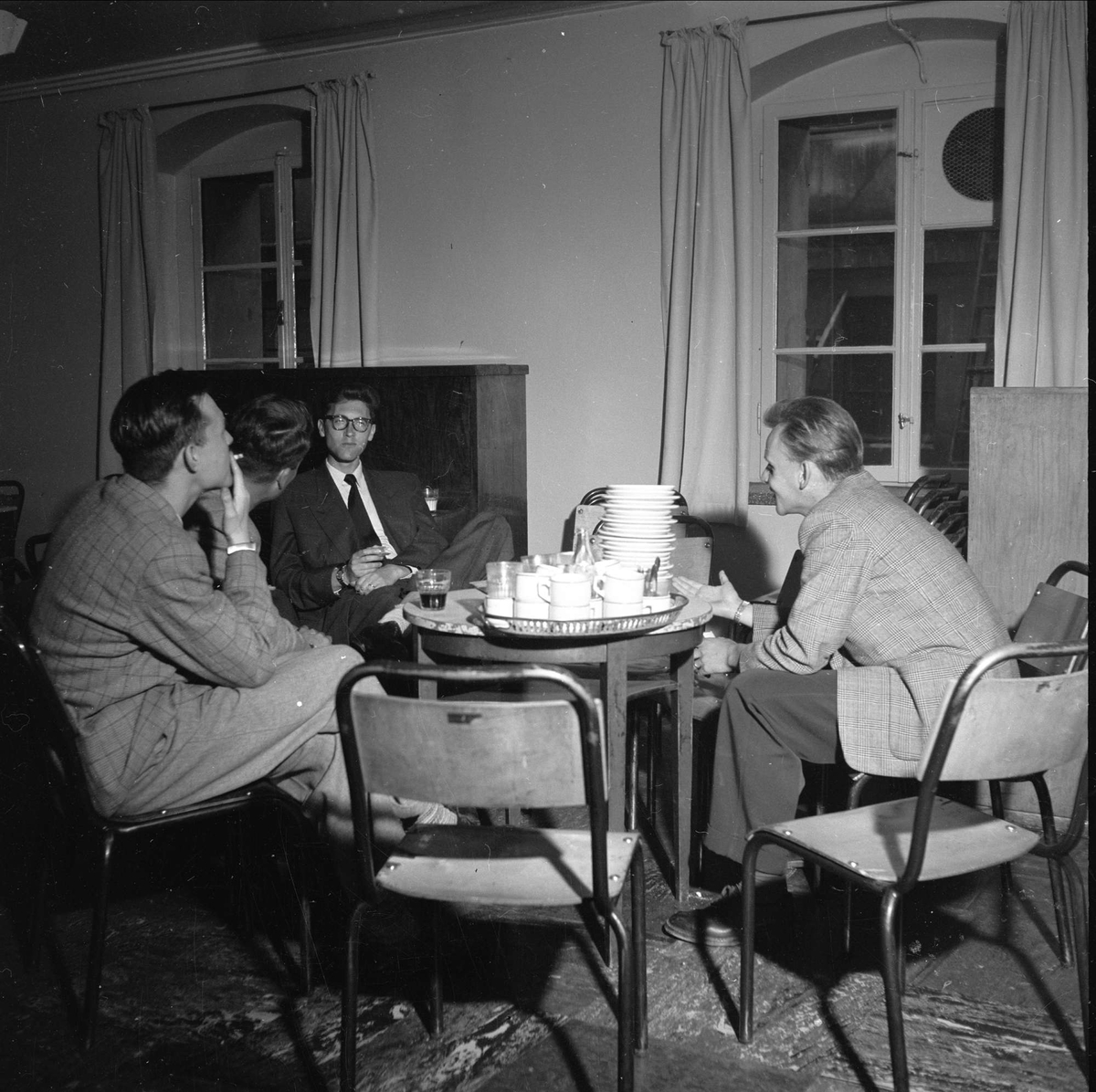 Karl Johans gate 47, Oslo, 09.08.1956. Universitetet. Unge menn rundt bord med skåler og kopper.