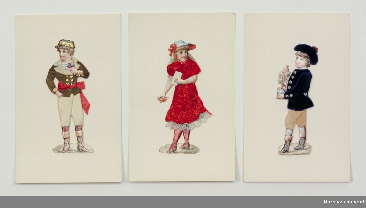 Katalogkort:
"Pappersdocka, leksak (bokmärke?). 3 st. tryckta pappersfigurer föreställande barn, uppfodrade på vit kartong, iklädda kläder delvis av tyg och skinn.Omkr. 1900."