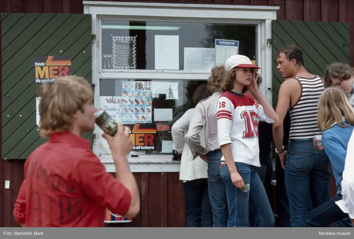 Ungdomar. Kiosk vid Sandvikens campingplats, Väddö. Några ungdomar i jeans står och hänger utanför kiosken. 