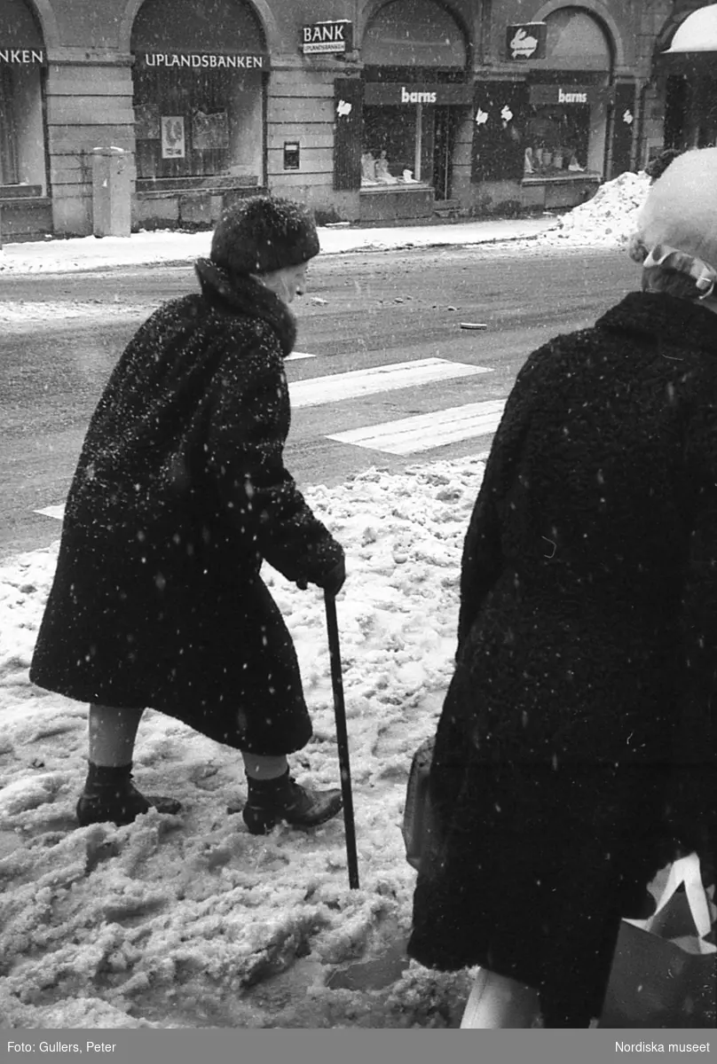 Äldre kvinna med käpp på snöig trottoar. Östermalm, Stockholm