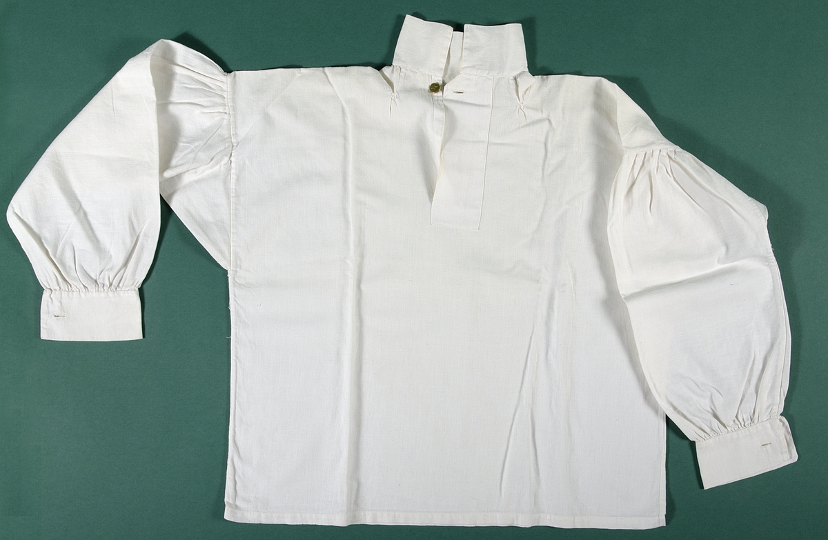 Skjorta, huvudsakligen maskinsydd av vitt linnetyg vävt i tuskaft. Skjortan har halsspjäll, krage och förslag. Ärmarna har lagda veck mot axlarna och de är rynkade mot ärmlinningarna. Förslaget och ärmlinningarna knäpps med platta knappar av gulmetall.

Skjortan är något smutsig och den är sliten vid halsspjällen.