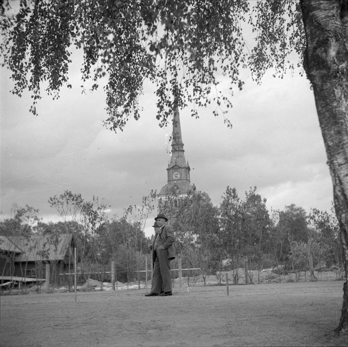 Två män på gården utanför Zornmuseet, Mora, Dalarna 1939. I bakgrunden syns Mora kyrka