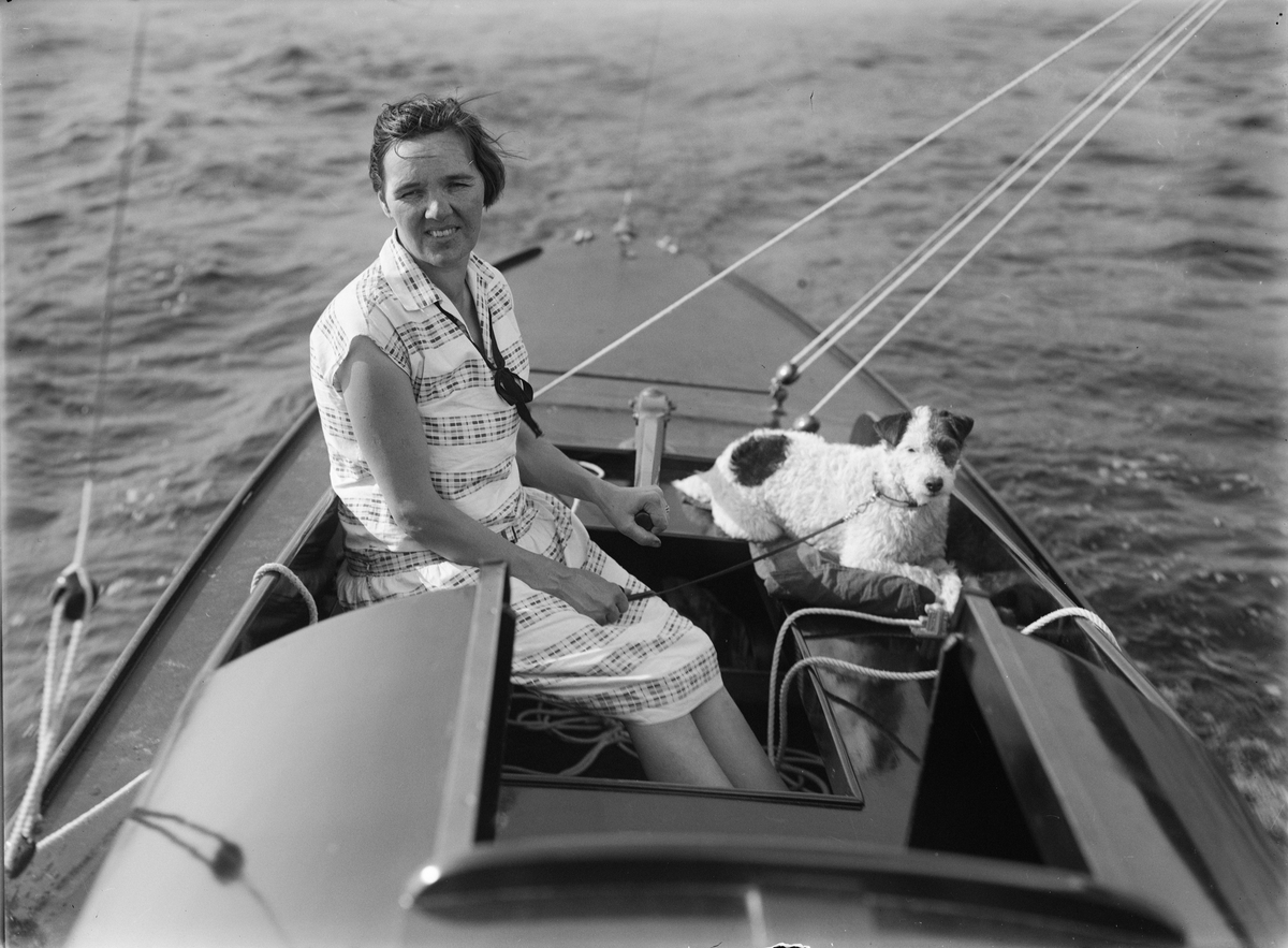Kvinna och hund i segelbåt, sannolikt på Ekoln, Uppland