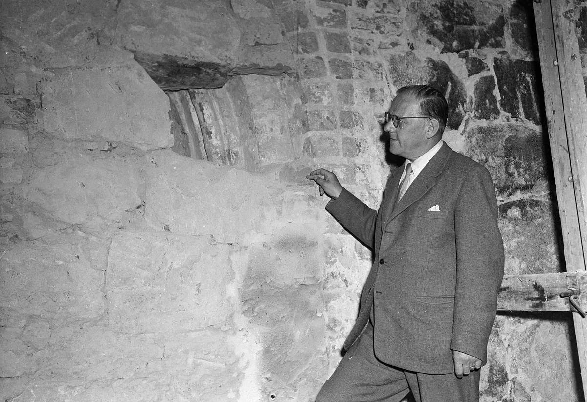 Landsantikvarie Nils Sundquist "vid den återfunna ärkedjäknens värdighetsportal i Bälinge kyrka", Bälinge, Uppland juli 1956