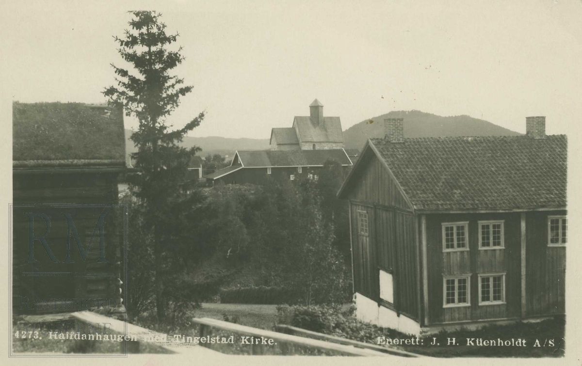 Utsikt fra Halvdanshaugen på Hadeland Folkemuseum mot sør med del av Skute stua, låven på Tingelstad, Tingelstad gamle kirke og del av Grinakerbygningen. 