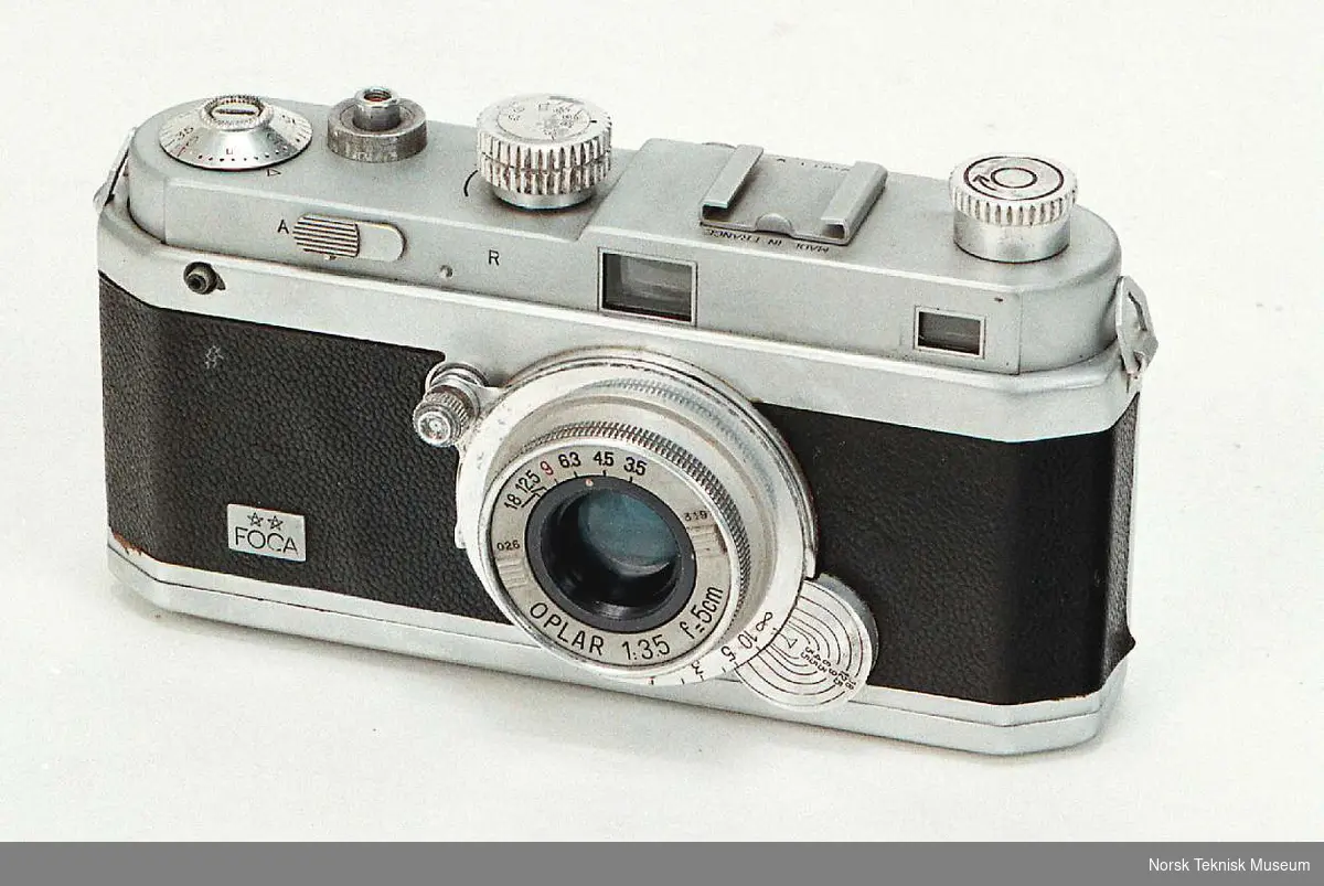 Fransk produsert 35mm kamera
Objektiv: Oplar 1:3,5  f=5cm
No. 49971 B
Gardinlukker
Veske 
