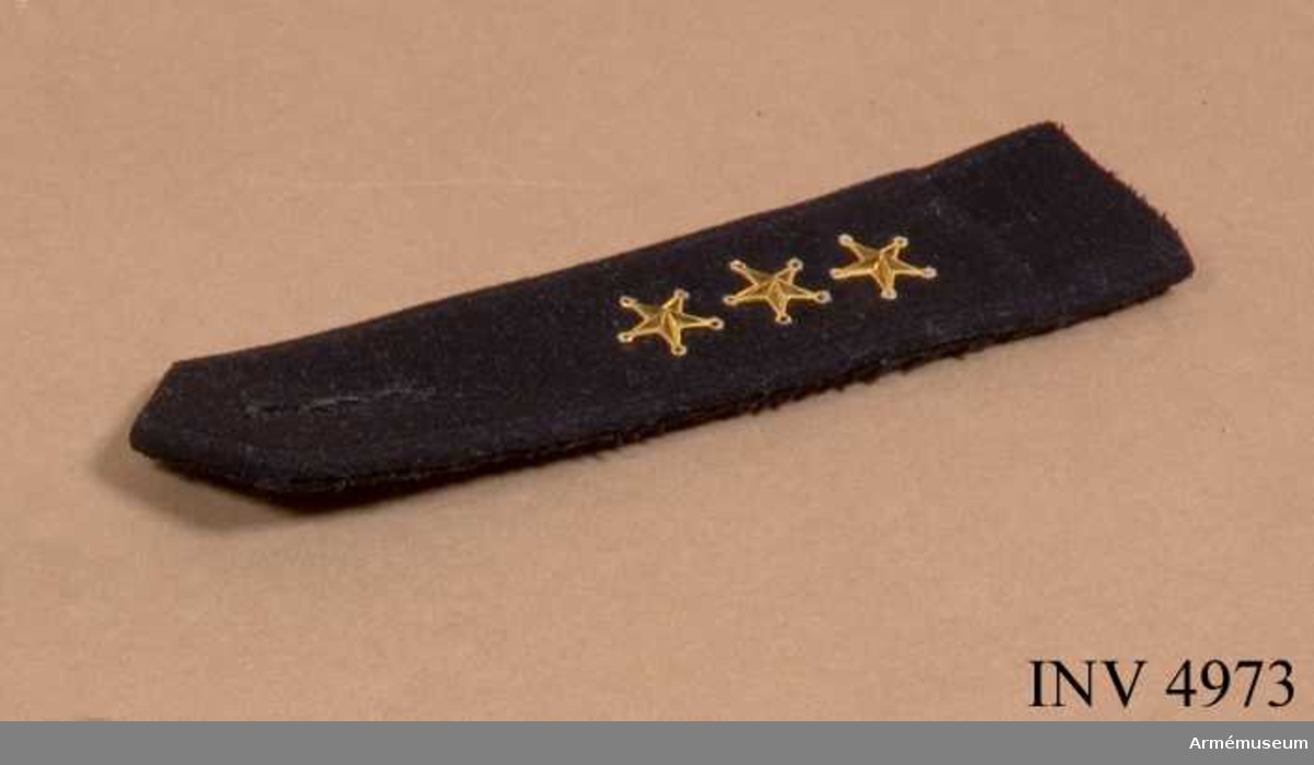 Av mörkblått (svart) kläde med knapphål / gradbeteckning för kapten = tre guldstjärnor m/1858.