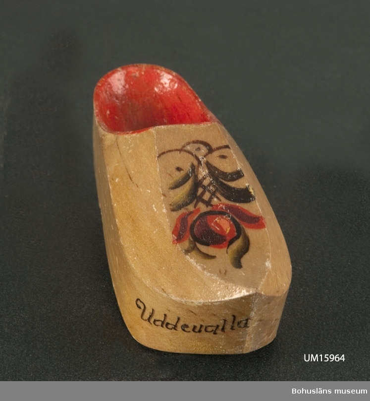 Miniatyrtoffel, inuti rödmålad, utanpå prydd med målad blomma och namnet "Uddevalla".

Se UM015810
