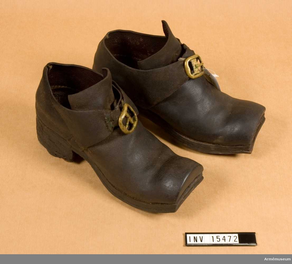 Ett par skor av brunt läder med mässingsspännen.