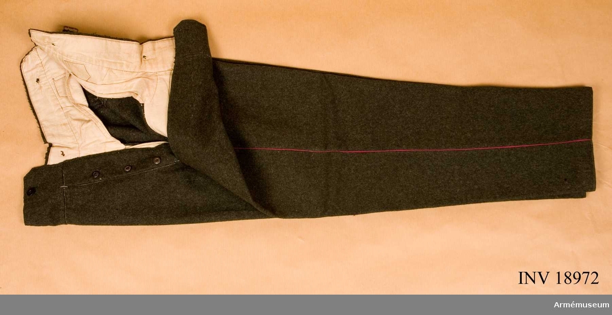 Långbyxor av grågrönt kläde (kaki), tillhörande uniform för manskap, Norge. Två fickor på sidan och spänntamp av kläde med järnspännen. På framsidan gylf som knäpps  med 4 järnknappar och för hängslena 6 likadana knappar. Byxorna har passpoal av karmosinrött kläde. Foder av oblekt bomullstyg med stämpel "IR..." -resten oläsligt. "Smaalenenes infanteri regimente N:r 1. (Fredrikstad)".

Den kompletta uniformen består av vapenrock,långbyxor lägermössa, vantar, strumpskaft, skidkängor, livrem, med patronväskor och bajonetthylsa.

Grupp C I.