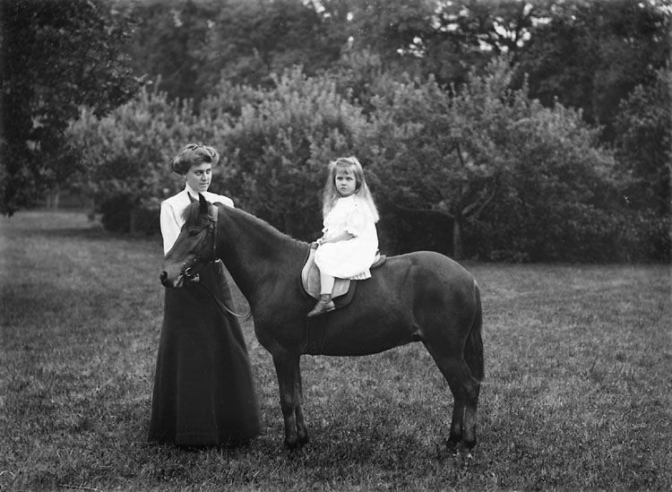 Enligt noteringar: "Häst med flicka på ryggen. Troligen någon av familjen Sörensens sommargäster." (BJ)