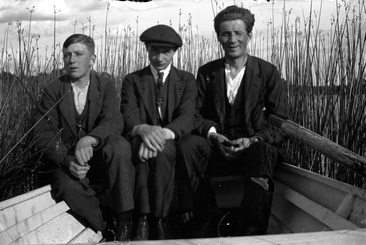 Tre män, Gustav Andersson i mitten, sitter i en roddbåt omgiven av vass.  Lungkliniken, Eksjö.