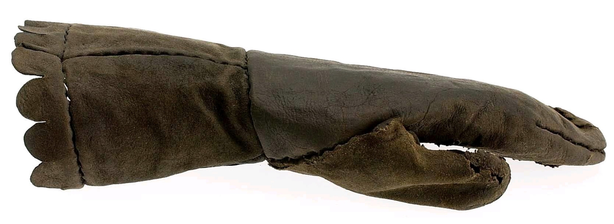 En kragvante till vänster hand. Sydd av flera kraftiga läderstycken. Påsydd bård i ett stycke i form av rundade "tungor" längs kragkanten.