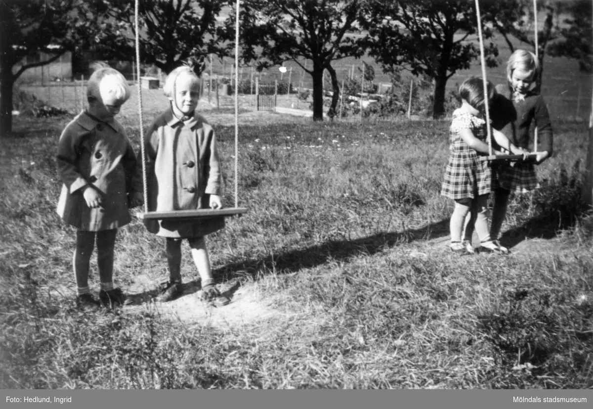 Bosgårdens barnträdgård 1938. Fyra barn som står parvis vid var sin gunga.