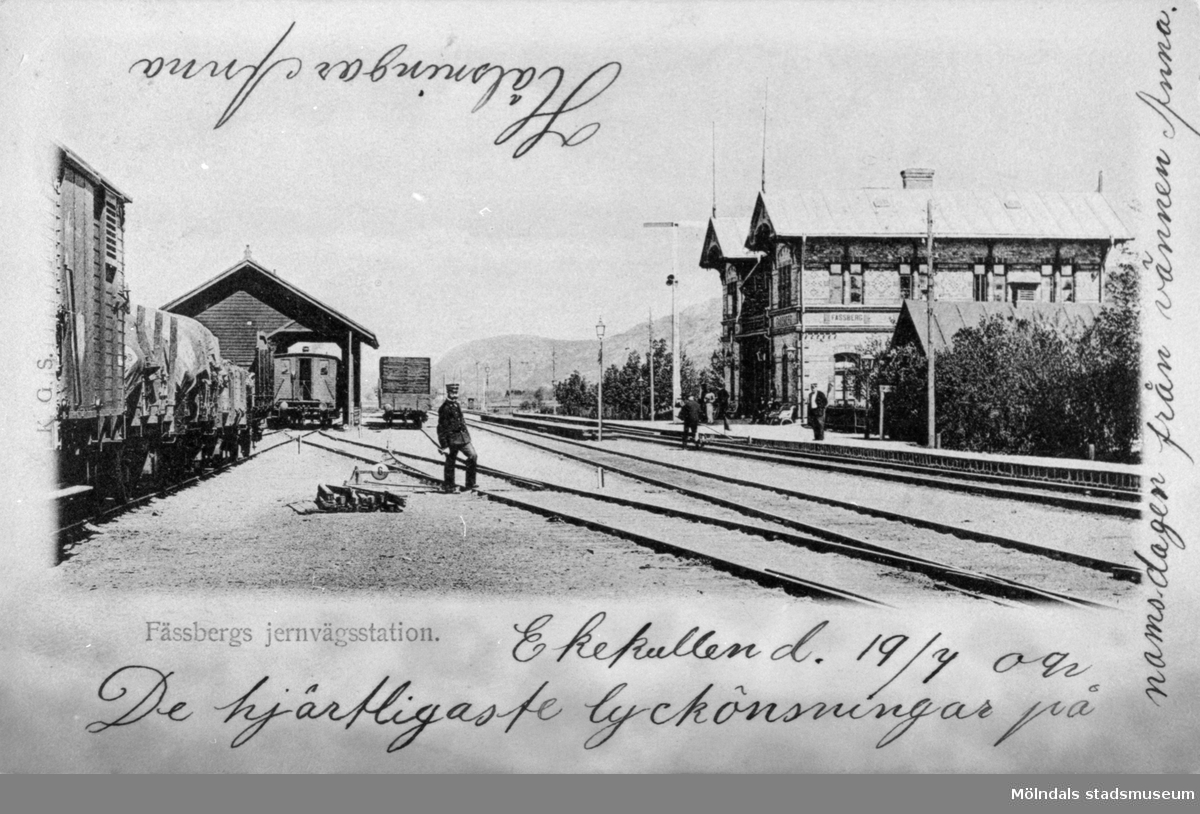 Vykort "Fässbergs jernvägsstation" poststämplat 20/7 1902. Järnvägsstationen, som 1922 fick namnet Mölndals Nedre, är fotograferad från sydväst. Man ser även ett godsmagasin. I bakgrunden till höger syns Lackarebäcksfjället och längre bort Rallarberget.