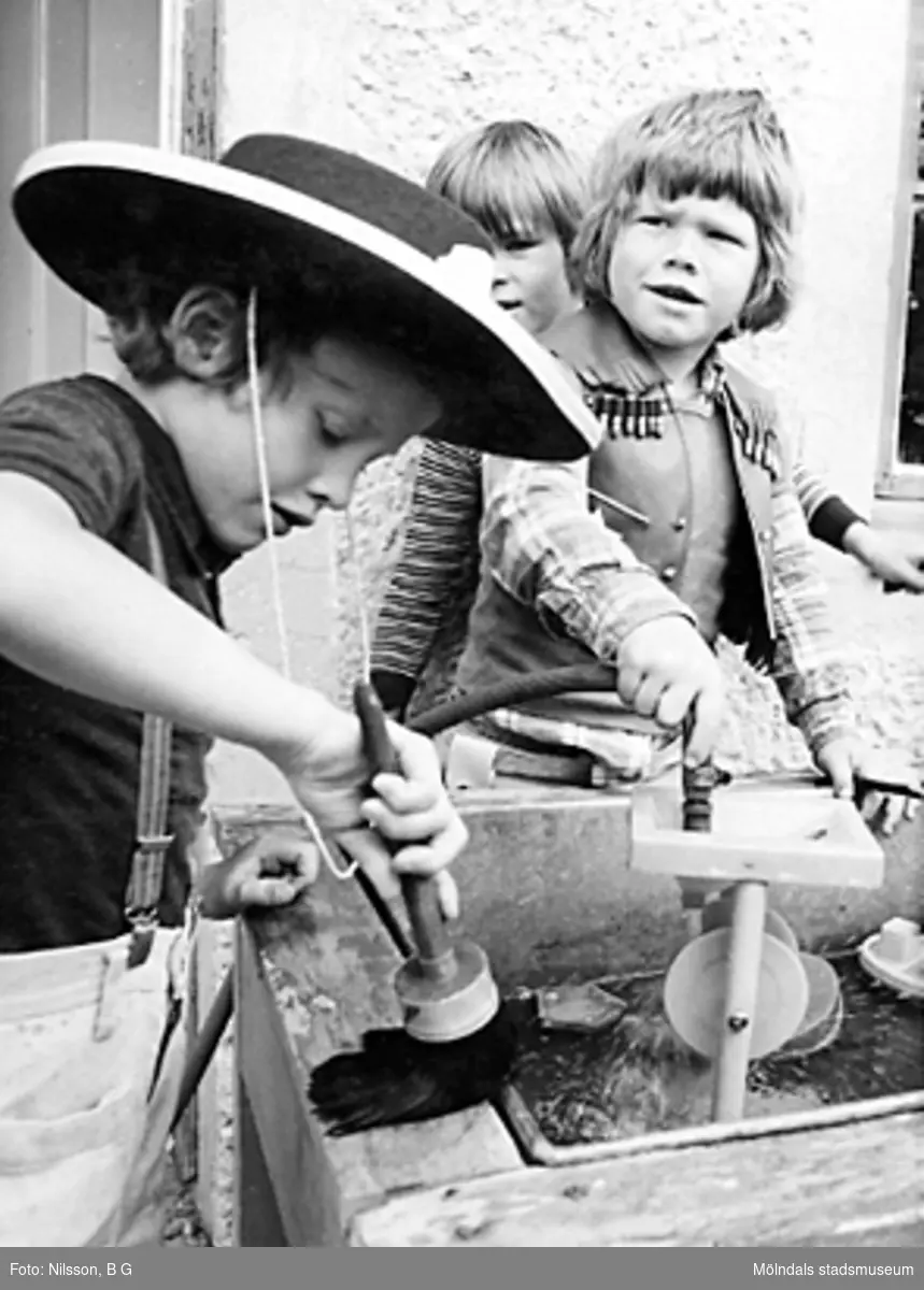 Tre barn som leker med verktyg utomhus. Holtermanska daghemmet juni 1974.