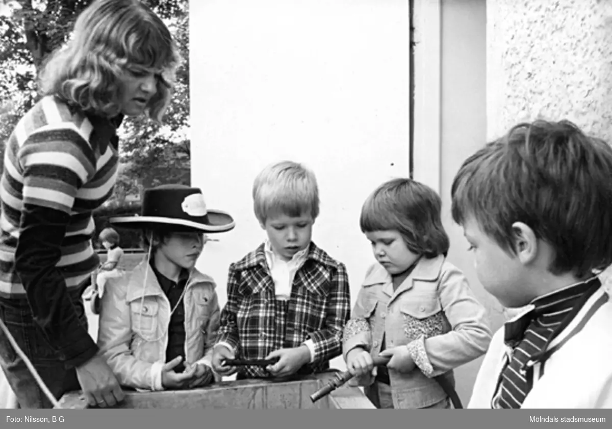 En fröken och fyra pojkar står samlade runt en behållare. Holtermanska daghemmet juni 1974.