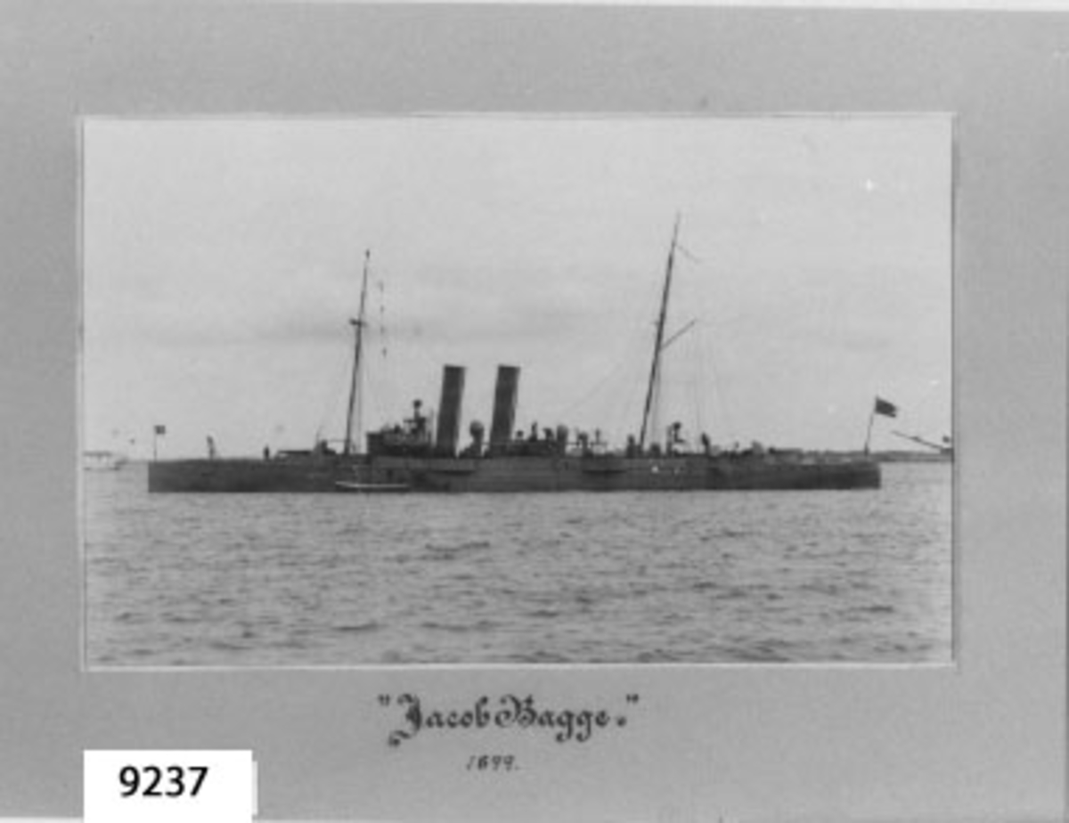 Fotografi inom ram av papp, grå. Visar torpedkryssaren JACOB BAGGE till ankars på Karlskrona redd år 1899.
Märkning i svart: Jacob Bagge.