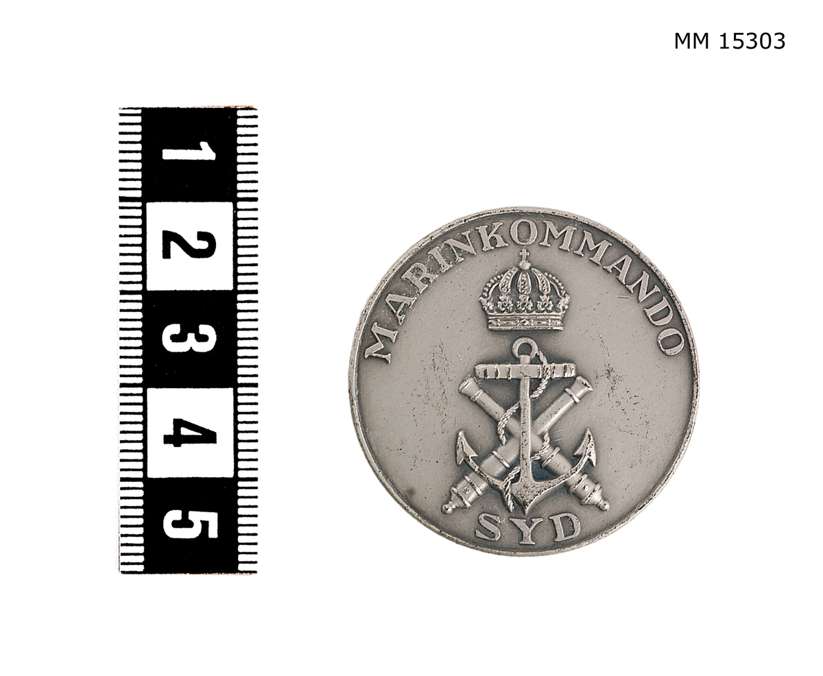 Rund medalj med marinens emblem krönt med en sluten kunglig krona. Över står med versala bokstäver: MARINKOMMANDO SYD. På baksidan en lagerkrans, öppen upptill.