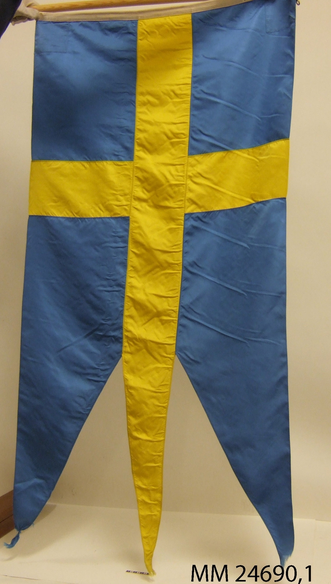 Svensk tretungad örlogsflagga. Liket vitt. På liket fastsydd lapp med texten: GRETA ZACHAU'S FLAGGFABRIK AB STOCKHOLM.