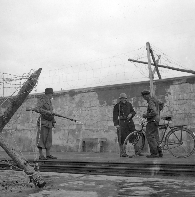 Vid spärren till yttre hamnen i Visby avfordras en hamnarbetare passersedel. Fil lic Gunnar Jonssons undersökningsresa till Gotland 1940.