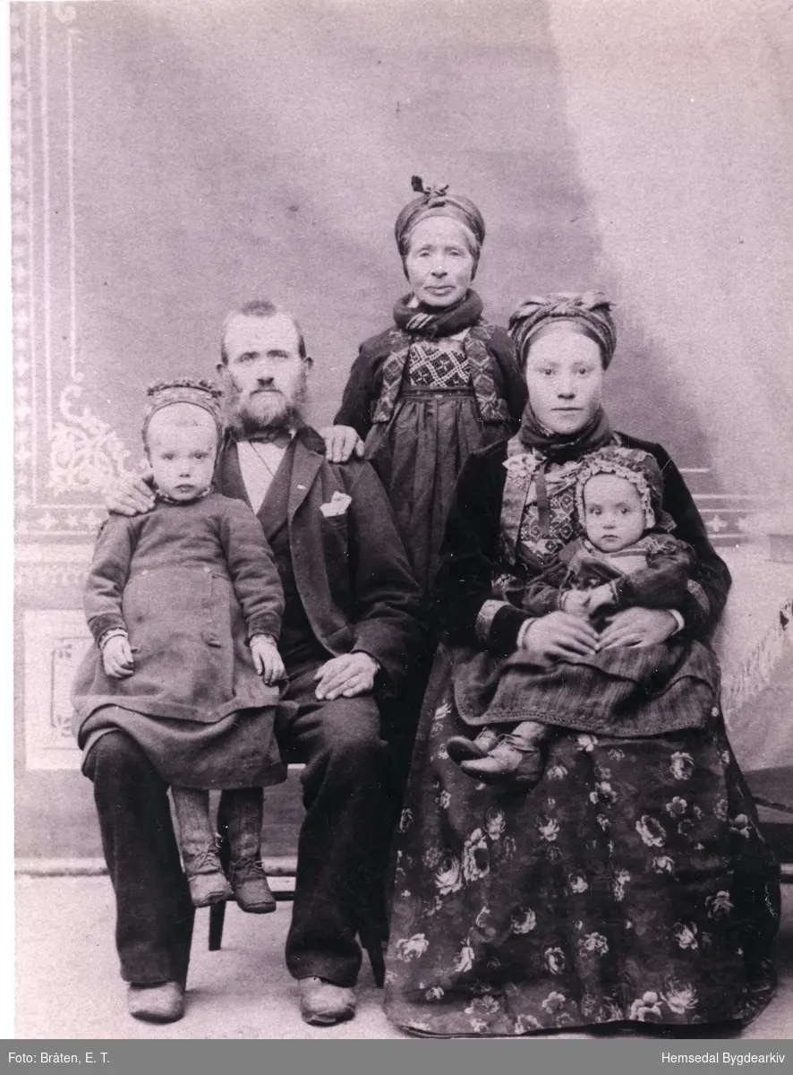 Bygdebokskrivaren, Hans  Flaten (1858-1930) og kona hans Birgit Ingvardsdotter Båste (1865--)
Bak dei to står mor til Hans, Margit Håkonsdotter Bergo (1826-1906)
Borna er: Olav, fødd 1888  og Margit, fødd 1889
