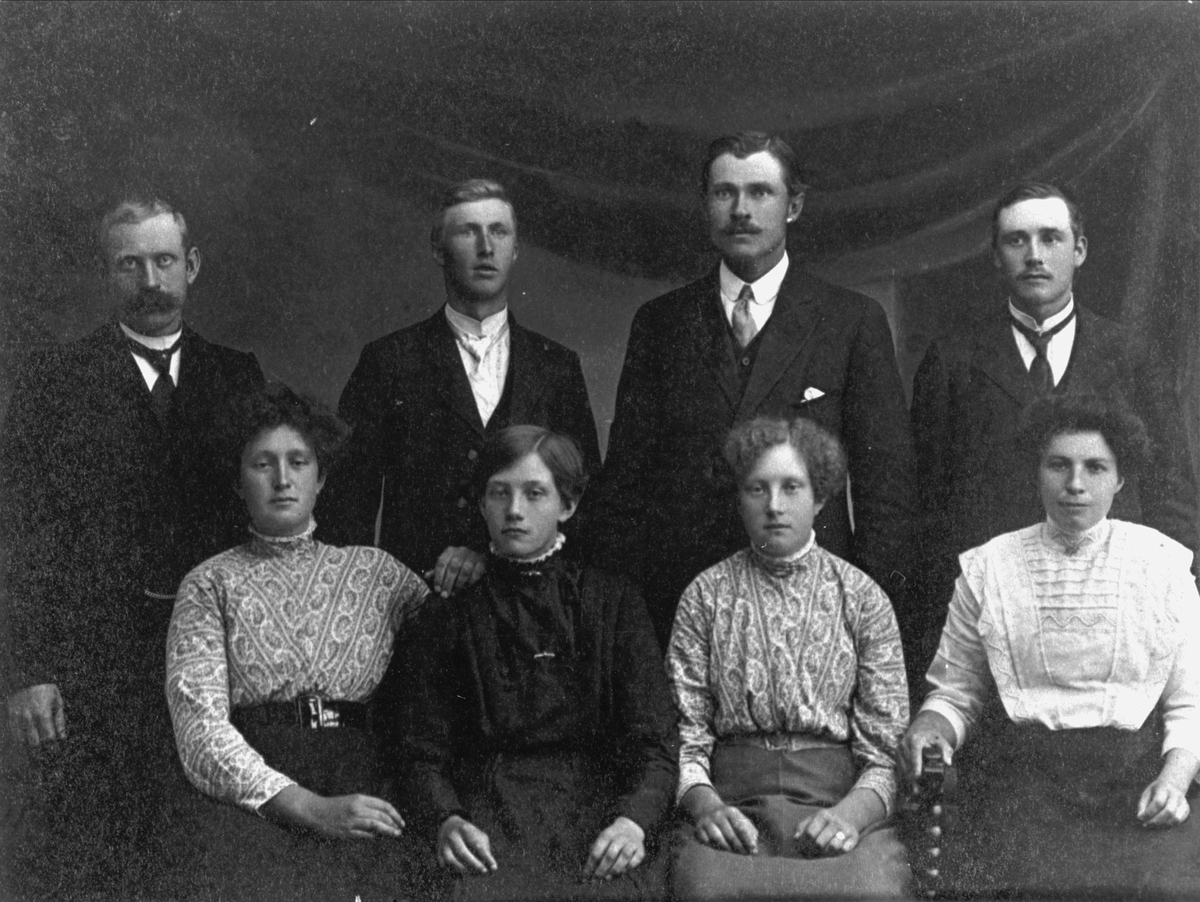 Gruppeportrett av åtte kvinner og menn. Knut Ingvald Knutsen bakerst til venstre.