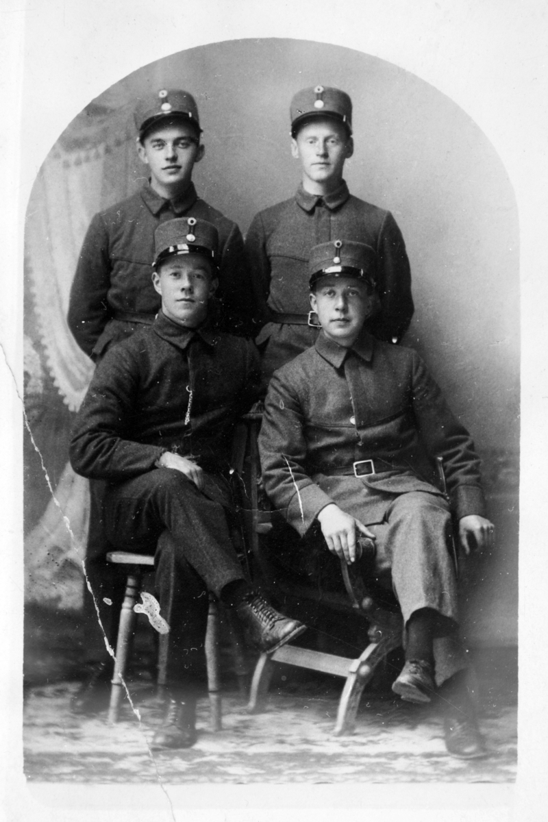 Studioportrett av fire soldater i helfigur.