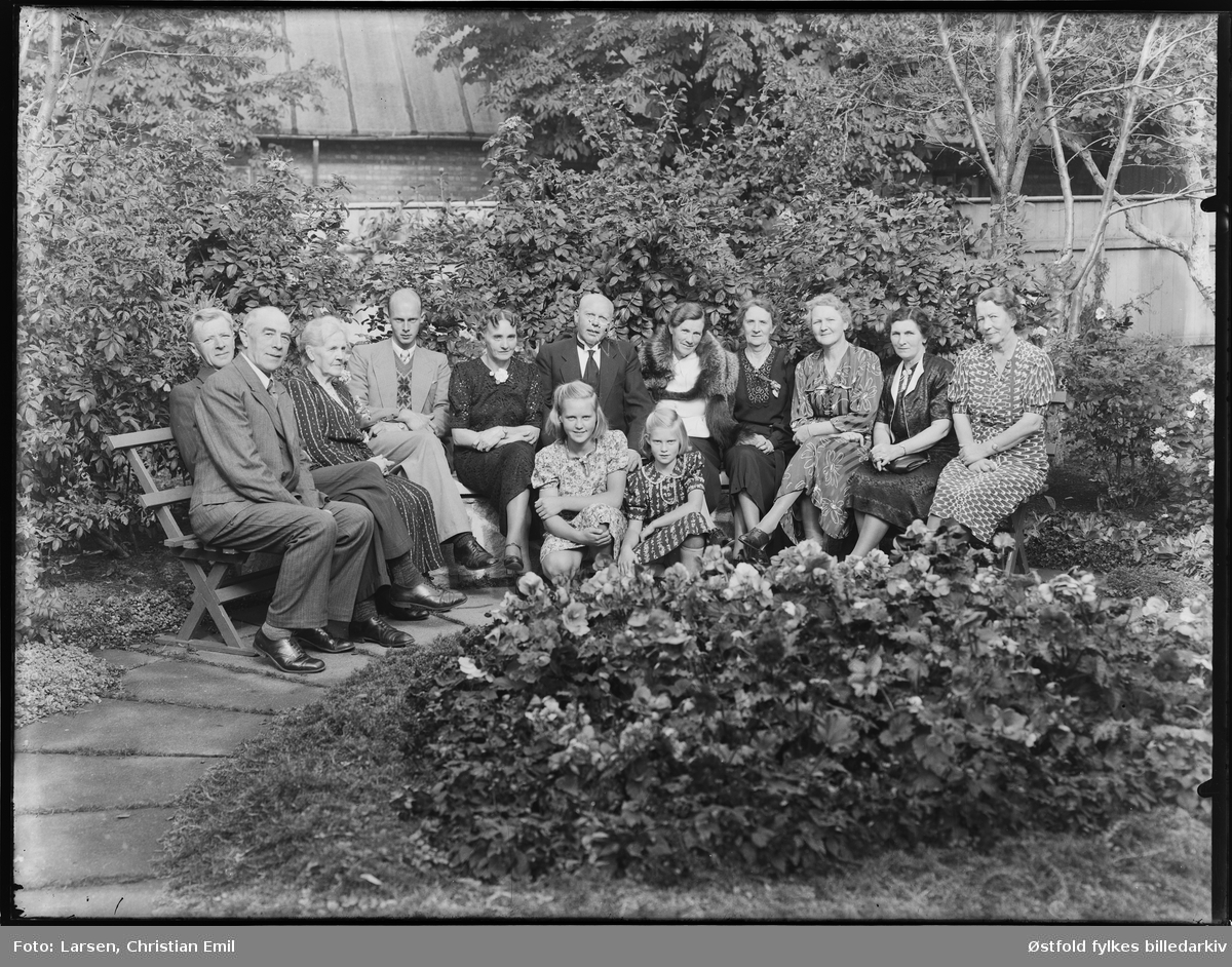Gruppe - antakelig familie samlet i en hage i en bakgård, ant- Sarpsborgdistriktet. Ukjent sted og personene er ukjente.