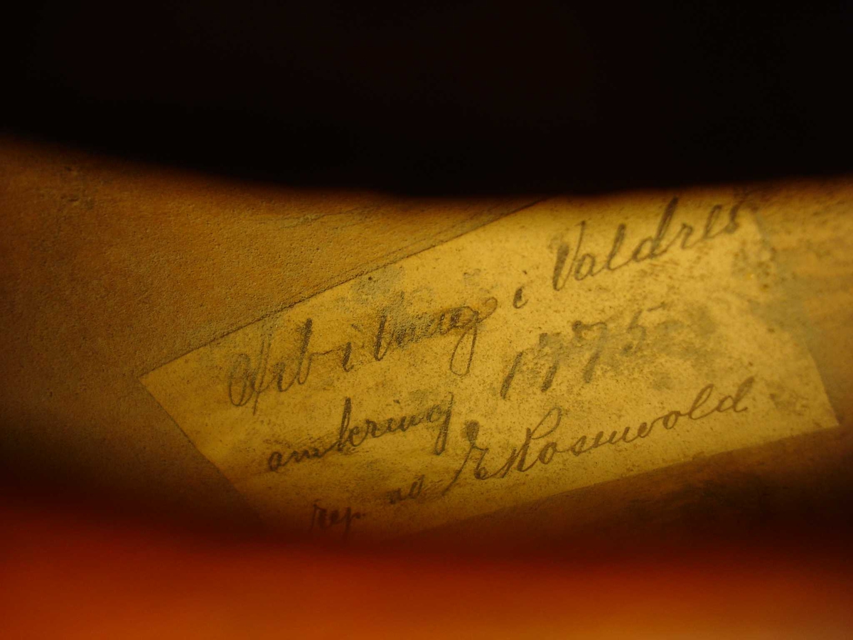 Fele med fire strenger. Løvehode med drakelignande trekk. På ein lapp på innsida av fela står det skreve at dette er "arbeid frå Vang i Valdres, omkring 1775". Fela er reparert av E. Rosenvold.