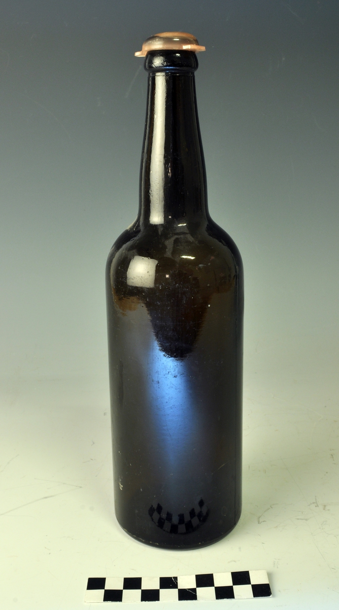 Stor ølflaske "gammel" form. Mørkebrunt glass. Plastkork.