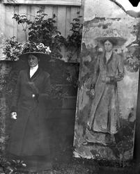 Kvinne med kåpe og blomsterpyntet hatt i hage, E.Munchs male