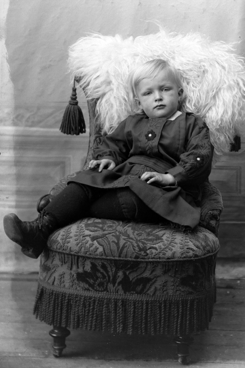 Studioportrett av et barn i en lenestol.