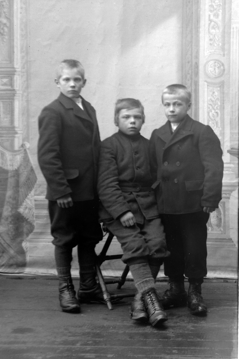 Studioportrett i helfigur av tre unge gutter.