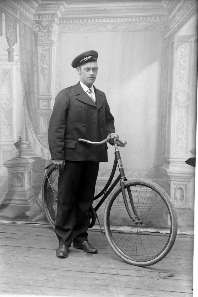 Studioportrett av en mann med kasjettlue og sykkel.