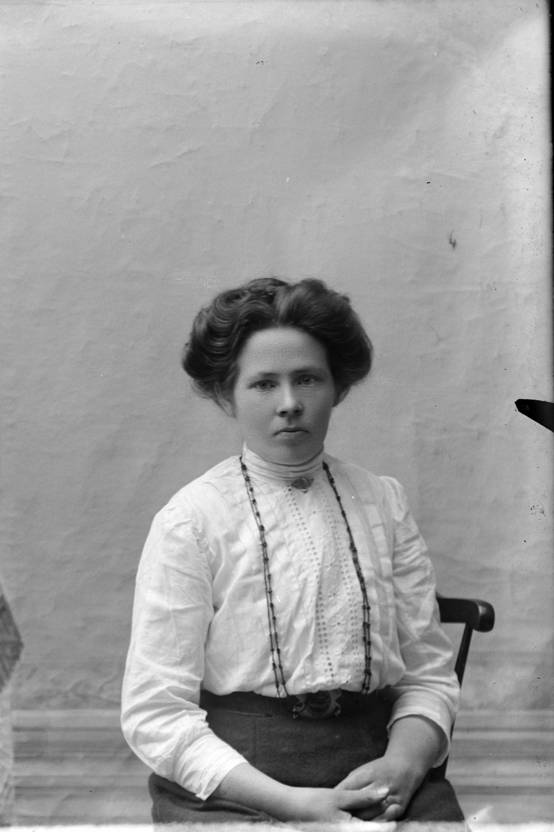 Studioportrett av en kvinne med langt smykke rundt halsen.