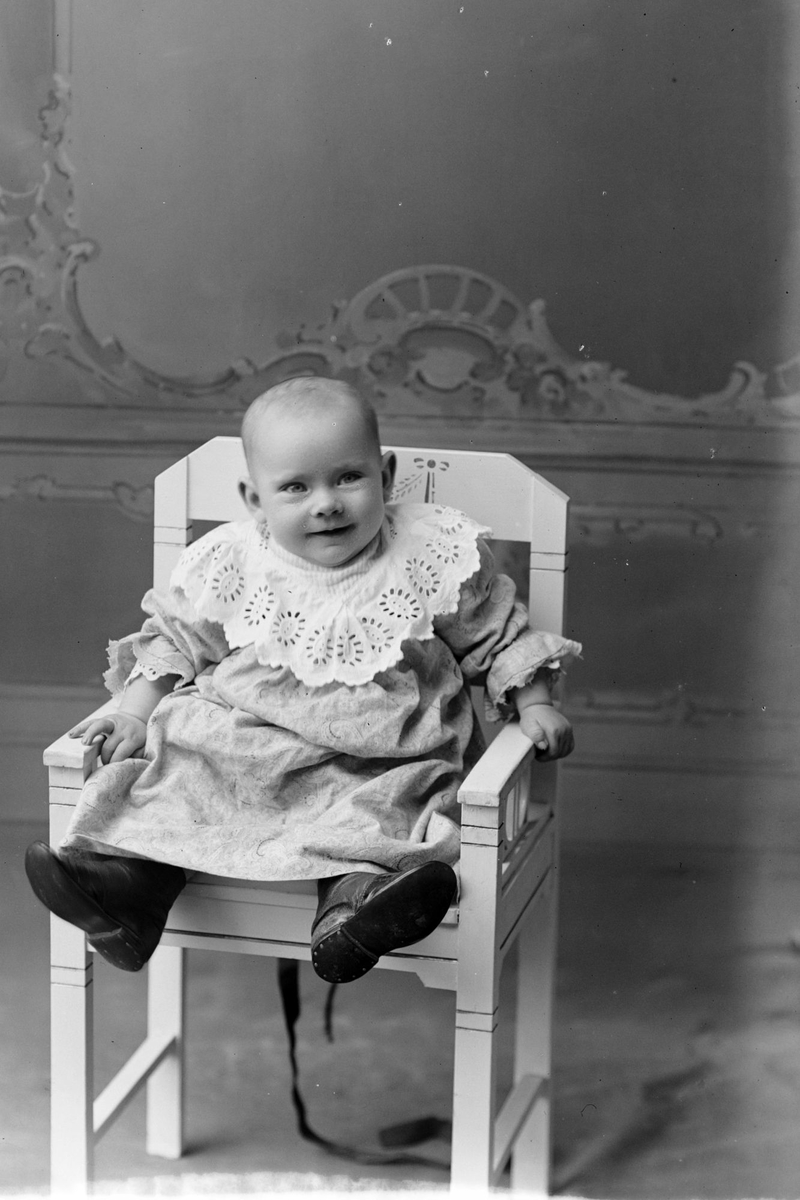 Studioportrett av et barn sittende på en stol.