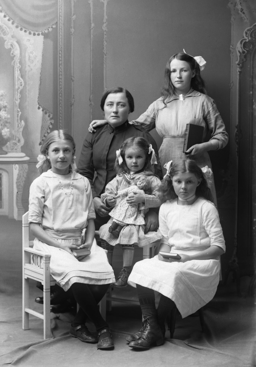 Studioportrett av en kvinne med fire jenter rundt seg.