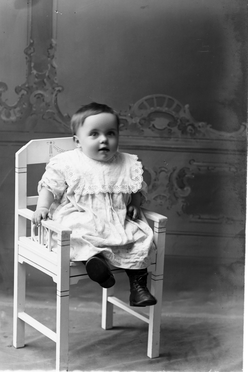 Studioportrett av et lite barn i en stol.