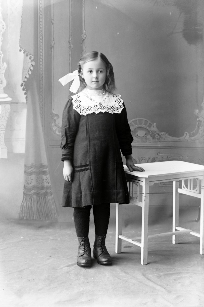 Studioportrett av en liten jente med sløyfe i håret.