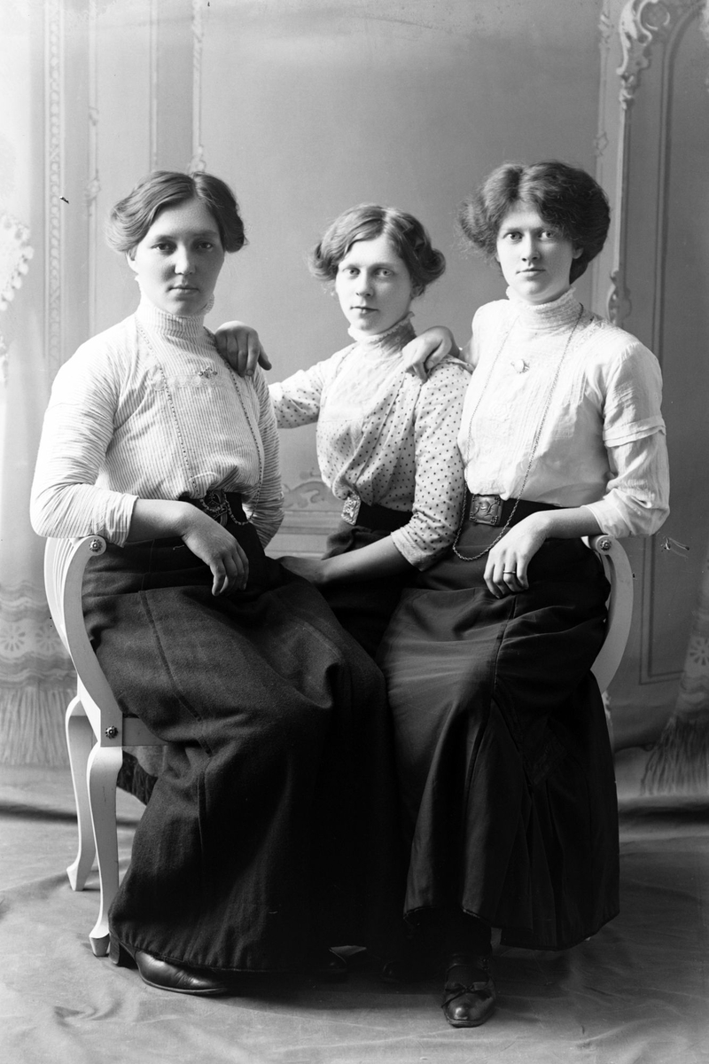Studioportrett av tre kvinner som sitter.