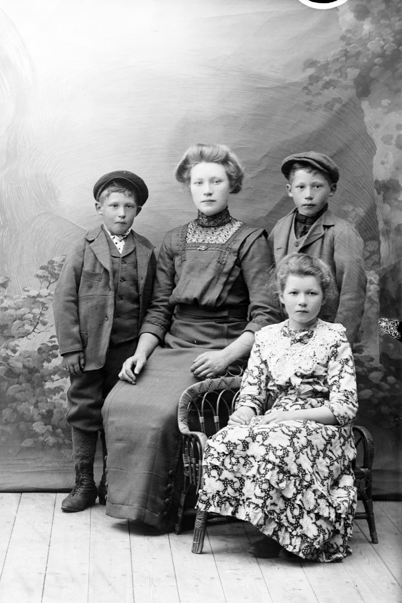 Studioportrett av en ung kvinne og tre barn.