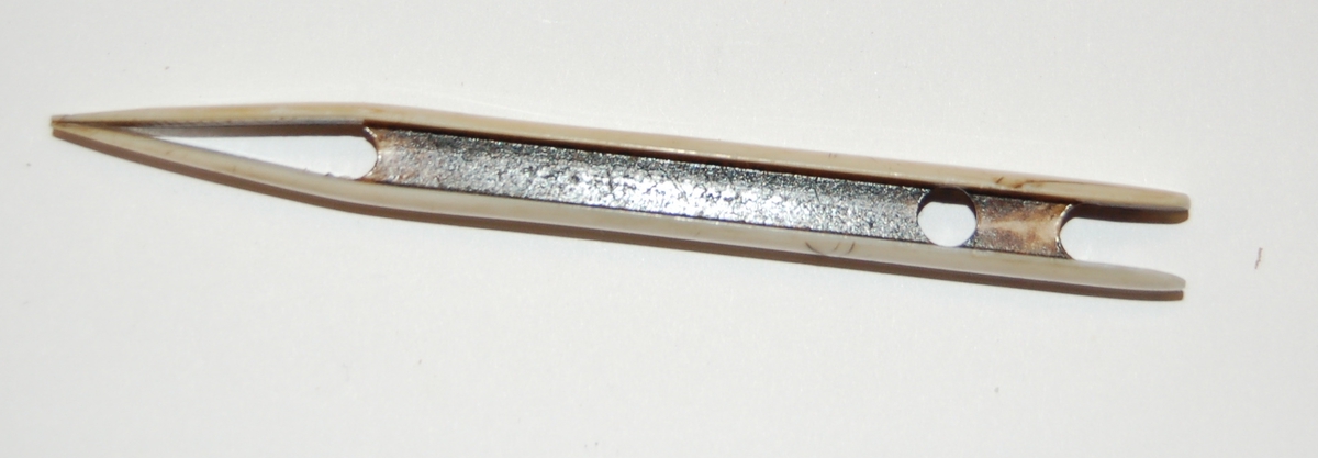 Nålen har en rektangulær form. I nålen er det utfreset et spor som tråden skal spoles opp på, og munnen på nålen er nebbformet med splittet ende.